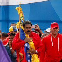 Venezuelan President Nicolas Maduro holds the Venezuelan flag next to singer "El Potro Alvarez" during a rally in Caracas on Thursday