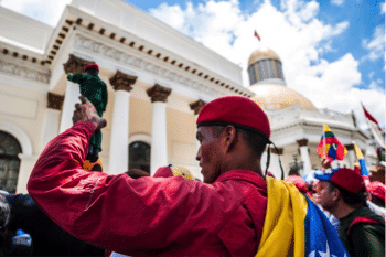 | A man holds a Chávez action figure in front of the Legislative Palace | MR Online