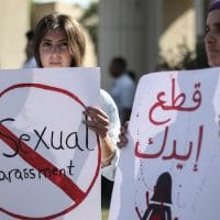 Ladies holding signs against sexual harassment.