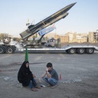 An Iranian couple rest as they sit in front of the Iranian surface-to-surface Zelzal missile while visiting an exhibition to mark the anniversary of the Iran-Iraq war (1980-88) at a Revolutionary Guard Corps military base in northeastern Tehran, September 26, 2011. © Morteza Nikoubazl. Exhibition to mark the anniversary of the Iran-Iraq war (1980-88)