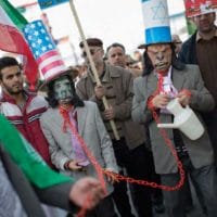 Iranian protestors wear masks as well as hats with the U.S. flag and Israeli flags
