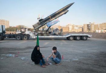 | An Iranian couple rests as they sit in front of the Iranian surface to surface Zelzal missile | MR Online
