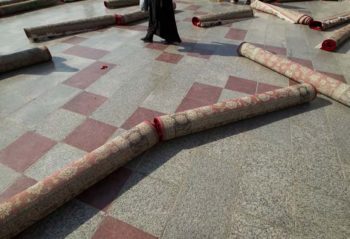 | An Iranian woman walks around rolled up carpets after the festival of Eid al Fitr | MR Online