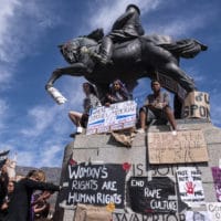 Protesters used the statue of Louis Botha outside Parliament in Cape Town as a vantage point and a pinboard for posters
