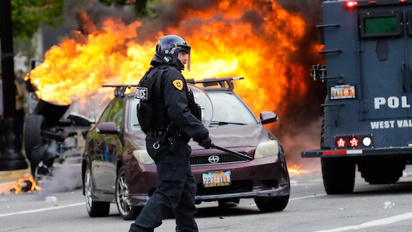 | A policeman walks in front of a burning vehicle as protesters demonstrate May 30 2020 in Salt Lake City Rick Bowmer | AP | MR Online