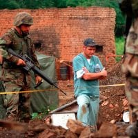 US Marines provide security as members of the Royal Canadian Mounted Police Forensics Team investigate a grave site in a village in Kosovo on July 1, 1999