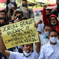An Indonesian trade unionist with a sign reading "Labor is not a slave, cancel the omnibus bill of job creation" in Jakarta