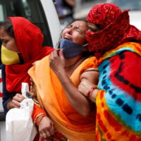 A woman is consoled after her husband died due to the coronavirus disease (COVID-19) outside the mortuary of a COVID-19 hospital in Ahmedabad, India, April 20, 2021