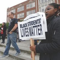 Felecia Bazie, 18, a senior and president of Associated Student Government at Garfield High School, holds signs following a “Black Lives Matter” rally Oct. 19, 2016 at the school in Seattle. Teachers, students and parents across Seattle public schools wore “Black Lives Matter” shirts to promote racial equity in schools. (AP Photo/Ted S. Warren)