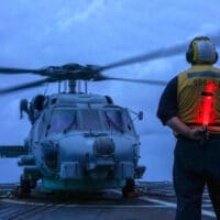 U.S. seaman on a guided-missile destroyer directs a helicopter during operations in the South China Sea in 2020. (U.S. Navy, Andrew Langholf)