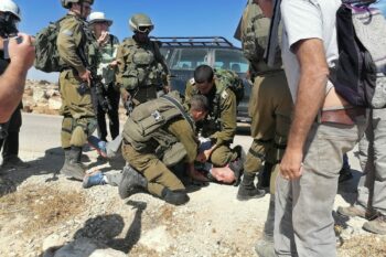 | An Israeli soldier kneels on the neck of an Israeli left wing activist during an attempt to bring water to Palestinian communities in the South Hebron Hills April 17 2021 | MR Online