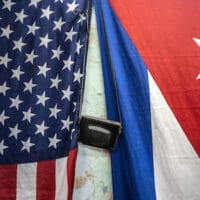 U.S. and Cuban flags hang from a wall with an old photo camera hung in between in Havana, Cuba, Monday, Jan. 11, 2021. Ramon Espinosa | AP