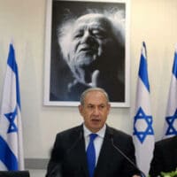 Prime Minister Benjamin Netanyahu stands in front of a portrait of Israel's first Prime Minister, David Ben-Gurion.