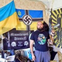 Azov fighter posing in front of Nazi posters, Mariupol, Ukraine.