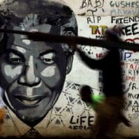 People walk past a mural of former South African President Nelson Mandela in Katlehong, south of Johannesburg, South Africa.