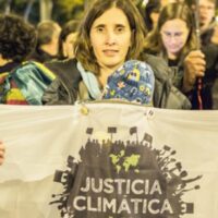 A protester holds up a sign that reads "Climate Justice" (in Spanish). Photo: Friend of the Earth