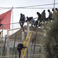 African migrants sit on top of a border fence during an attempt to cross from Morocco into Spain's north African enclave of Melilla, November 21, 2015. Photo: Reuters/Jesus Blasco de Avellaneda/File Photo