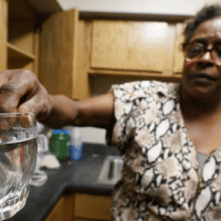 A resident displays contaminated water in her kitchen in Jackson, Miss. (AP Photo/Steve Helber)