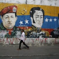 | A man walks past a mural depicting Venezuelas late President Hugo Chávez Latin American independence hero Simon Bolivar and Venezuelas President Nicolás Maduro in Caracas Photo by Marco Bello | MR Online
