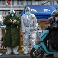 Epidemic control workers wear PPE to prevent the spread of COVID-19 as they stand next to equipment for cold weather in an area where some communities are under lockdown on Nov. 29, 2022, in Beijing, China.