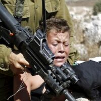 IOF soldier restraining Palestinian boy in Ramallah, Palestine ,August 28, 2015 (Photo: Reuters)