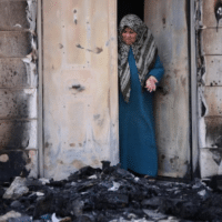 A Palestinian woman examines damage caused by the Jewish settler pogrom in the town of Huwwara, in the occupied West Bank. (Photo: Oren Ziv, via ActiveStills.com)