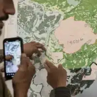 People look at a map of the fire in Fort Chipewyan, Alberta on Friday, June 2, 2023. Over 800 people have been evacuated from Fort Chipewyan as wildfires threaten the community downriver from the oil sands. Amber Bracken