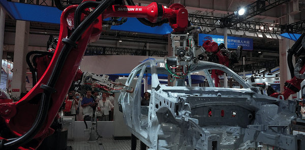 | Visitors watch robotic arms assemble a car during the World Robot Conference in Beijing last week | MR Online