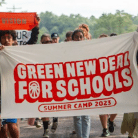 Young organizers hold up a banner celebrating the "Green New Deal for Schools Summer Camp 2023." (Photo: Sunrise Movement)