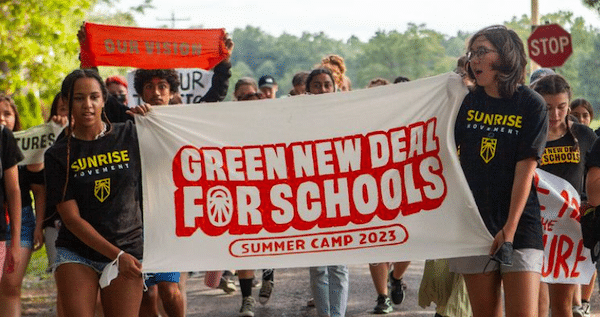 | Young organizers hold up a banner celebrating the Green New Deal for Schools Summer Camp 2023 Photo Sunrise Movement | MR Online