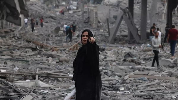 MR Online | Palestinians walk through debris amid the destruction from Israeli airstrikes in Gaza Citys al Rimal neighbourhood on 10 October 2023 AFP | MR Online