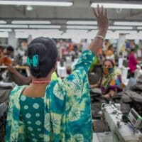 Pushpa Rani Shaha, gives a victory wave to fellow garment workers. Source: ILO Asia-Pacific - Flickr / cropped from original / shared under license CC BY-NC-ND 2.0