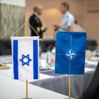 | A NATO and an Israeli table side flags on a blurred buffet table and two military officers talking Photo NATO Maritime CommandFile photo | MR Online