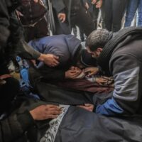 Palestinians grieve over the bodies of loved ones killed in Israeli bombardment of an encampment for displaced people in al-Mawasi, an area of Khan Younis in southern Gaza, 25 January. Mohammed Talatene DPA