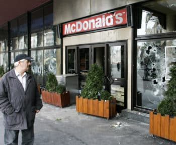 | A man looks at the broken windows of a McDonalds in Belgrade following a 2008 protest Darko Vojinovic | AP | MR Online