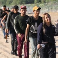 A group of migrants seeking U.S. asylum walk down a road beside the Rio Grande River to turn themselves in to the Border Patrol.
