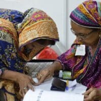 A polling official confirms a voter's identity during the Pakistani general elections in July 2018. Photo: Commonwealth Secretariat on Flickr