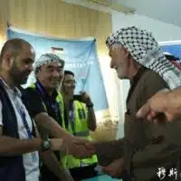 Zhang Chengzhi greeting a Palestinian refugee from Gaza in a Jordanian refugee camp, 2012.