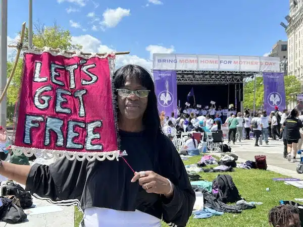 MR Online Part 12 | Avis Lee holds a banner for Lets Get Free the Women and Trans Prisoner Defense Committee which helped with her fight for freedom and with which she now organizes to free others | MR Online