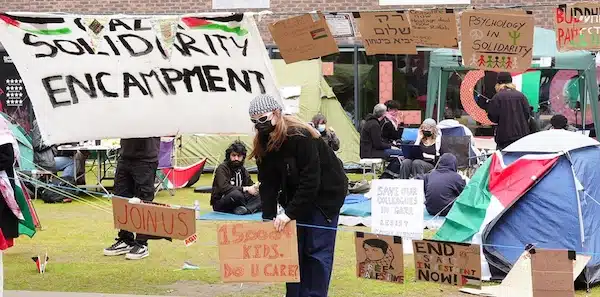 MR Online Part 6 | A student adjusts a sign at an encampment on the grounds of Newcastle University protesting against the war in Gaza May 2 2024 | MR Online